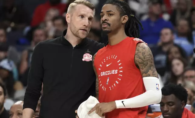 Memphis Grizzlies interim head coach Tuomas Iisalo, left, talks with guard Ja Morant, right, in the second half of an NBA basketball game against the Minnesota Timberwolves, Thursday, April 10, 2025, in Memphis, Tenn. (AP Photo/Brandon Dill)