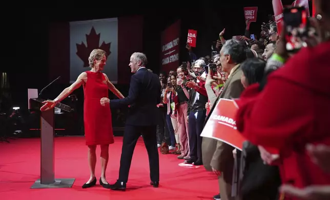Canadian Prime Minister Mark Carney embraces his wife Diana Fox Carney before addressing supporters at his campaign headquarters after the Liberal Party won the Canadian election in Ottawa, Ontario, Tuesday, April 29, 2025. (Sean Kilpatrick/The Canadian Press via AP)
