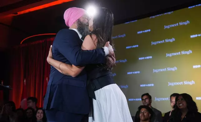 NDP Leader Jagmeet Singh kisses his wife Gurkiran Kaur as he pauses while addressing supporters on election night, in Burnaby, B.C., on Monday, April 28, 2025. (Darryl Dyck/The Canadian Press via AP)