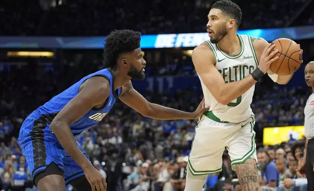 Boston Celtics forward Jayson Tatum, right, looks to pass the ball as he is defended by Orlando Magic forward Jonathan Isaac, left, during the first half in game 3 of a first-round NBA playoff basketball series,, Friday, April 25, 2025, in Orlando, Fla. (AP Photo/John Raoux)
