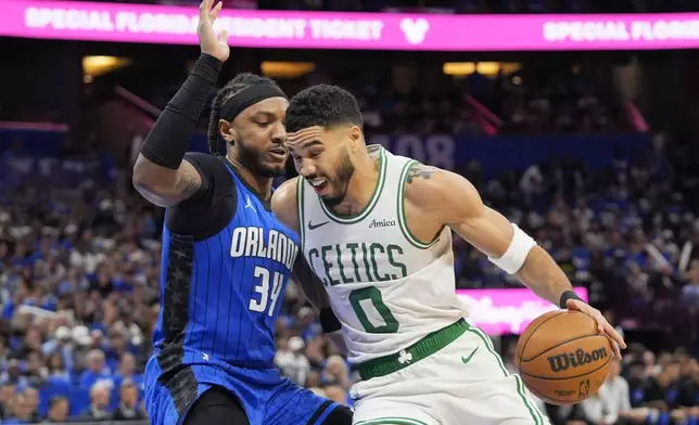 Boston Celtics forward Jayson Tatum (0) drives past Orlando Magic center Wendell Carter Jr. (34) during the first half in game 3 of a first-round NBA playoff basketball series,, Friday, April 25, 2025, in Orlando, Fla. (AP Photo/John Raoux)