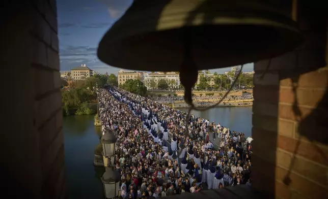 Penitents of the Estrella brotherhood walk in procession across the so-called Triana bridge during Holy Week in Seville., Spain, Sunday, April 13, 2025. (AP Photo/Emilio Morenatti)