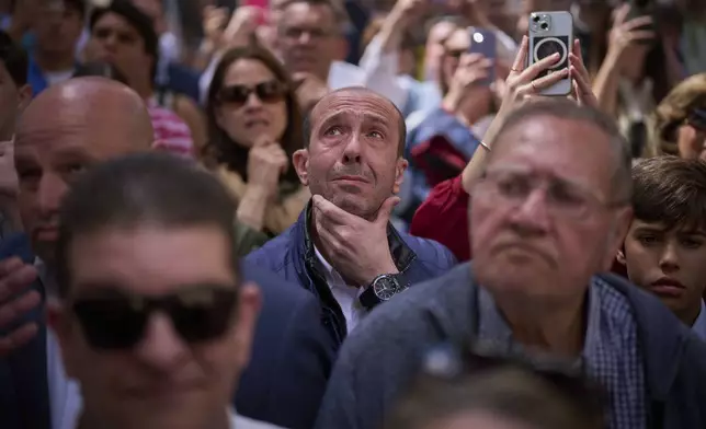 Worshipers react while looking at the Christ of the 'Santa Genoveva' brotherhood as they process through the streets of Seville during Holy Week in Spain, Monday, April 14, 2025. (AP Photo/Emilio Morenatti)