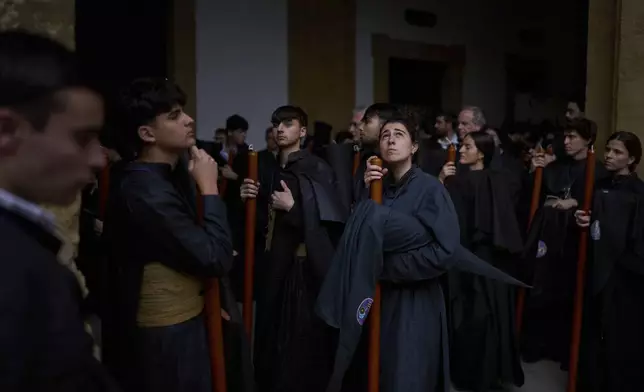 Penitents of the Los Estudiantes brotherhood look up at the sky after being told that they will not go out in procession due to the rain, that has cancelled several processions, during Holy Week in Seville, Spain, Tuesday, April 15, 2025. (AP Photo/Emilio Morenatti)