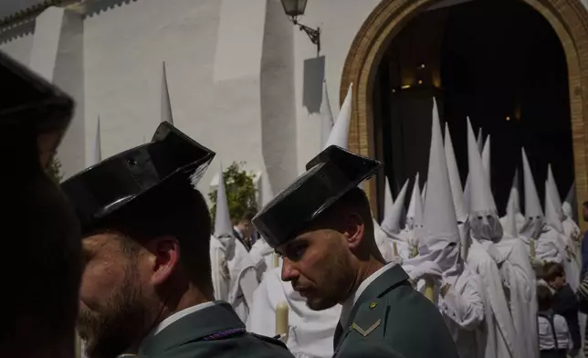 Guardia Civil officers guard the procession as the penitents of the brotherhood of 'La Paz' walk through the streets of Seville during Holy Week, Sunday, April 13, 2025. (AP Photo/Emilio Morenatti)