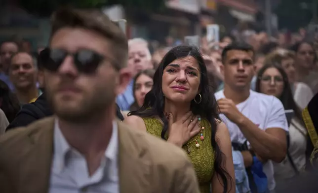 A woman reacts by crying as the Christ of the brotherhood of La Estrella is carried out of the church to process through the streets of Seville, during Holy Week in Spain, Sunday, April 13, 2025. (AP Photo/Emilio Morenatti)