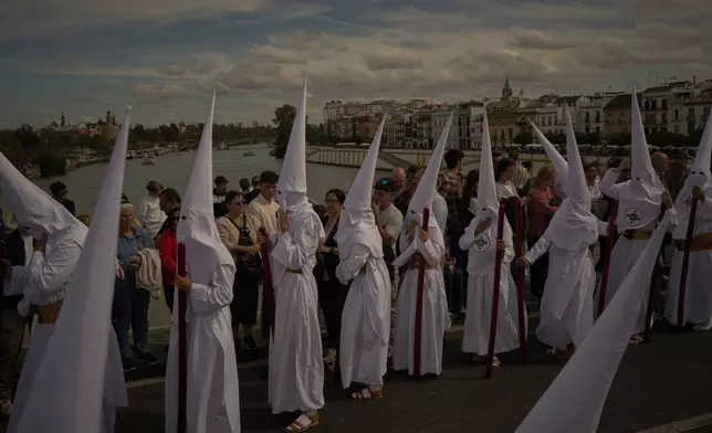 Penitents of 'San Gonzalo' brotherhood process through the streets of Seville during Holy Week in Spain, Monday, April 14, 2025. (AP Photo/Emilio Morenatti)
