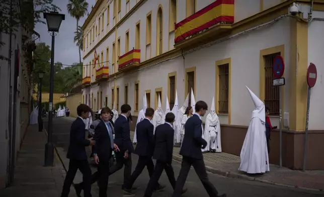 Penitents from "La Paz" brotherhood walk to the church to take part in a procession in Seville, Spain, Sunday, April 13, 2025. (AP Photo/Emilio Morenatti)