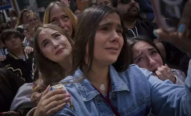 Worshipers react in tears while looking at the Christ of 'El Cerro' brotherhood as they process through the streets of Seville, during Holy Week in Spain, Tuesday, April 15, 2025.(AP Photo/Emilio Morenatti)