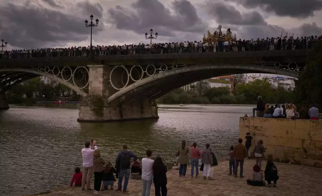 Penitents of 'San Gonzalo' brotherhood walk in procession across the so-called Triana bridge during Holy Week in Seville, Spain, Monday, April 14, 2025. (AP Photo/Emilio Morenatti)