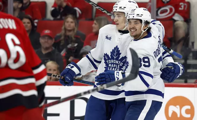 Toronto Maple Leafs' Pontus Holmberg, center, is congratulated on his goal by teammate Nicholas Robertson (89) during the first period of an NHL hockey game against the Carolina Hurricanes in Raleigh, N.C., Sunday, April 13, 2025. (AP Photo/Karl DeBlaker)