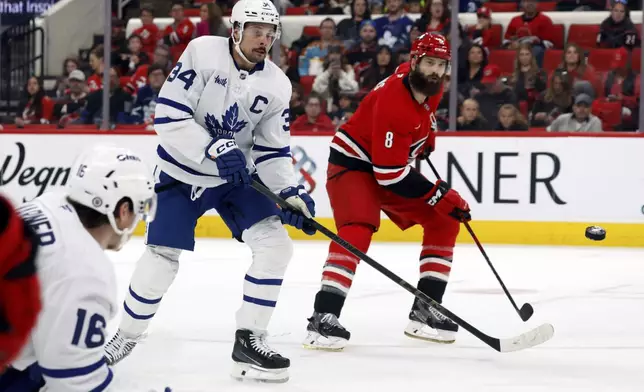 Carolina Hurricanes' Brent Burns (8) and Toronto Maple Leafs' Auston Matthews (34) watch the shot of Leafs' Mitch Marner (16) fly by during the second period of an NHL hockey game in Raleigh, N.C., Sunday, April 13, 2025. (AP Photo/Karl DeBlaker)