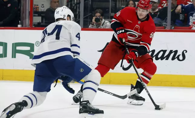 Carolina Hurricanes' Eric Robinson (50) controls the puck near Toronto Maple Leafs' Morgan Rielly (44) during the second period of an NHL hockey game in Raleigh, N.C., Sunday, April 13, 2025. (AP Photo/Karl DeBlaker)