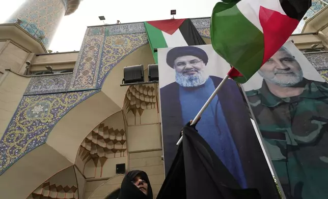 An Iranian protester waves the Palestinian flag in front of the portraits of Lebanon's Hezbollah former leader Hassan Nasrallah, left, who was killed by Israel and the late Iranian Revolutionary Guard Gen. Qassem Soleimani, who was killed in a U.S. drone attack in 2020, during an anti-Israeli demonstration at the Felestin (Palestine) Sq. in Tehran, Iran, Wednesday, April 9, 2025. (AP Photo/Vahid Salemi)