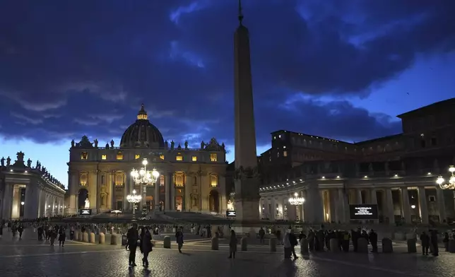 FILE - People walk at dusk in St Peter's Square at the Vatican, Thursday, Feb. 27, 2025. (AP Photo/Kirsty Wigglesworth, File)