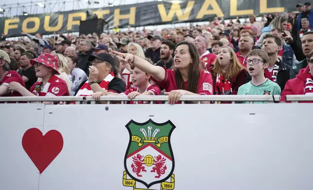 Wrexham fans watch the English League One soccer match between Wrexham and Charlton Athletic at the Racecourse ground in Wrexham, Wales, Saturday, April 26, 2025. (AP Photo/Jon Super)