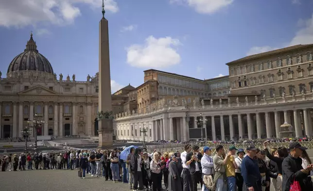 People queue in St. Peter's Square to pay their respect to the late Pope Francis, who will lie in state at St. Peter's Basilica for three days, at the Vatican, Wednesday, April 23, 2025. (AP Photo/Emilio Morenatti)