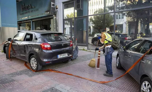 A municipal worker cleans the area outside Hellenic Train headquarters, Greece's main railway company, following a bomb explosion Friday night causing causing limited damage but no injuries, in Athens, Greece, on Saturday, April 12, 2025. (AP Photo/Yorgos Karahalis)