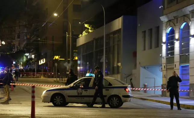 Policemen close the road after a suspected bomb explosion outside of the Hellenic Train offices the company that runs Greece's railway, the second building on the right, in Athens, Greece, Friday, April 11, 2025. (AP Photo/Petros Giannakouris)