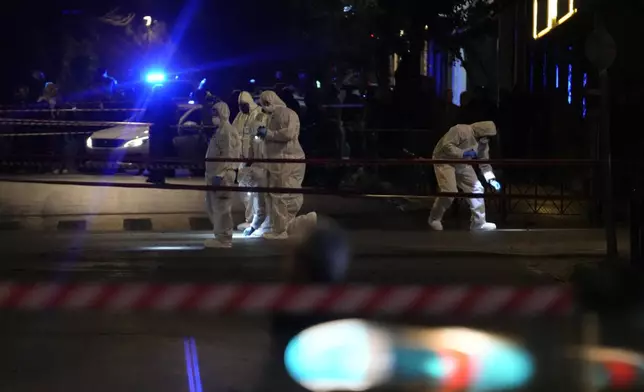 Police officers from the forensics department check the area after a bomb explosion outside of the Hellenic Train offices the company that runs Greece's railway, in Athens, Greece, Friday, April 11, 2025. (AP Photo/Petros Giannakouris)