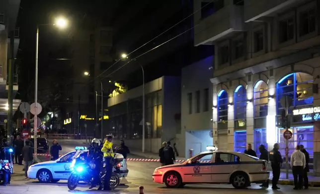 Policemen close the road after a suspected bomb explosion outside of the Hellenic Train offices the company that runs Greece's railway, the second building on the right, in Athens, Greece, Friday, April 11, 2025. (AP Photo/Petros Giannakouris)