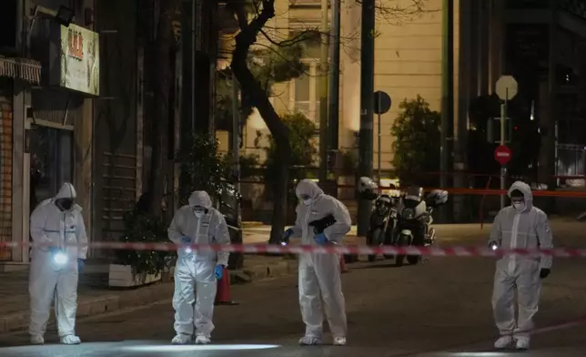 Police officers from the forensics department check the area after a bomb explosion outside of the Hellenic Train offices the company that runs Greece's railway, in Athens, Greece, Friday, April 11, 2025. (AP Photo/Petros Giannakouris)