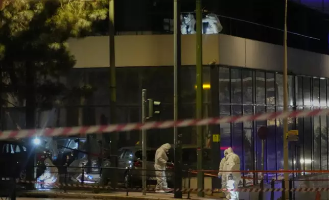Police officers from the forensics department check the area after a bomb explosion outside of the Hellenic Train offices the company that runs Greece's railway, in Athens, Greece, Friday, April 11, 2025. (AP Photo/Petros Giannakouris)
