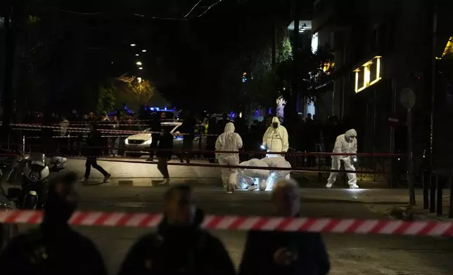 Police investigators wearing coveralls inspect the site after a bomb explosion outside of the Hellenic Train offices the company that runs Greece's railway, in Athens, Greece, Friday, April 11, 2025. (AP Photo/Petros Giannakouris)