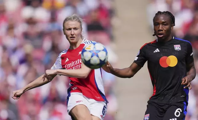 Arsenal's Leah Williamson takes a shot next to Lyon's Melchie Dumornay, right, during the women's Champions League semifinals, first leg, soccer match between Arsenal FC and Olympique Lyonnais at the Arsenal Stadium, in London, Saturday, April 19, 2025. (AP Photo/Kirsty Wigglesworth)