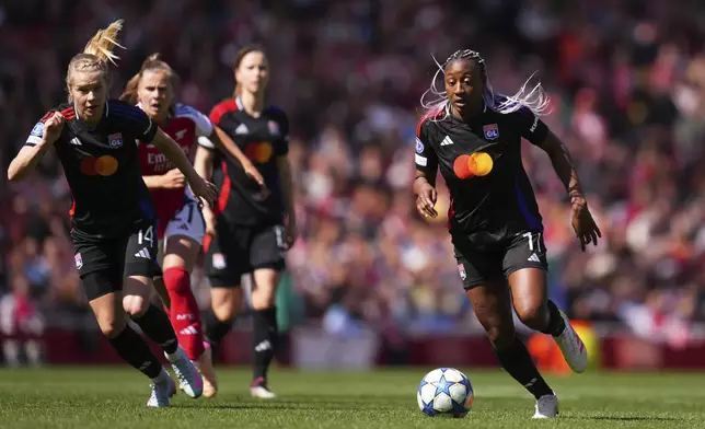 Lyon's Kadidiatou Diani runs with the ball watched by teammate Lyon's Ada Hegerberg, left, during the women's Champions League semifinals, first leg, soccer match between Arsenal FC and Olympique Lyonnais at the Arsenal Stadium, in London, Saturday, April 19, 2025. (AP Photo/Kirsty Wigglesworth)