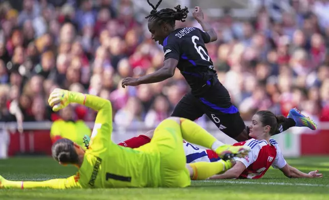 Lyon's Melchie Dumornay scores her side's second goal past Arsenal's Emily Fox, right, and Arsenal goalkeeper Manuela Zinsberger, foreground, during the women's Champions League semifinals, first leg, soccer match between Arsenal FC and Olympique Lyonnais at the Arsenal Stadium, in London, Saturday, April 19, 2025. (AP Photo/Kirsty Wigglesworth)