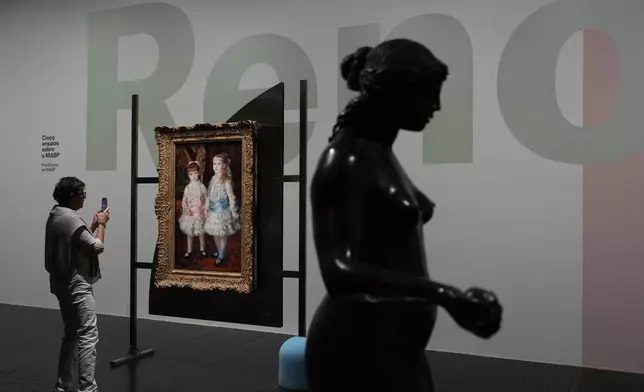 A visitor takes a photo of the "Pink and Blue - The Cahen d´Anvers Girls" painting by French impressionist Pierre-Auguste Renoir, at the Sao Paulo Art Museum or MASP, in Sao Paulo, Thursday, April 10, 2025. (AP Photo/Andre Penner)