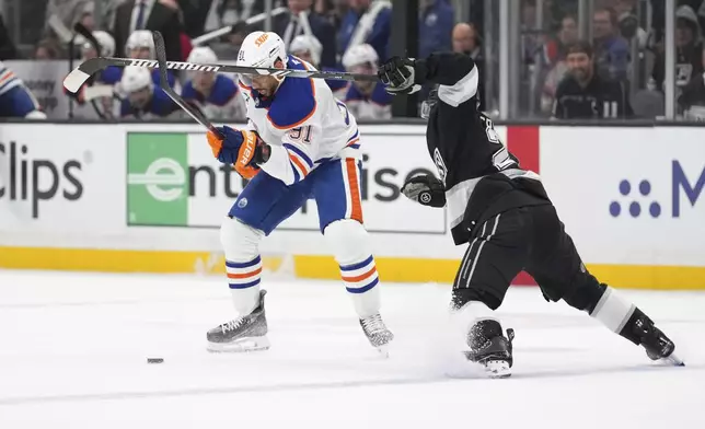Los Angeles Kings defenseman Jordan Spence, right, puts pressure on Edmonton Oilers left wing Evander Kane during the first period in Game 2 of an NHL hockey first-round playoff series Wednesday, April 23, 2025, in Los Angeles. (AP Photo/Mark J. Terrill)