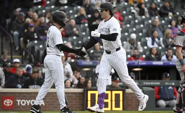 Colorado Rockies' Mickey Moniak (22) and Michael Toglia (4) celebrate after a home run by Toglia in the second inning of a baseball game against the Atlanta Braves Tuesday, April 29, 2025, in Denver. (AP Photo/Geneva Heffernan)