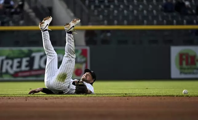 Colorado Rockies second baseman Kyle Farmer (6) falls to the ground in the second inning of a baseball game against the Atlanta Braves Tuesday, April 29, 2025, in Denver. (AP Photo/Geneva Heffernan)