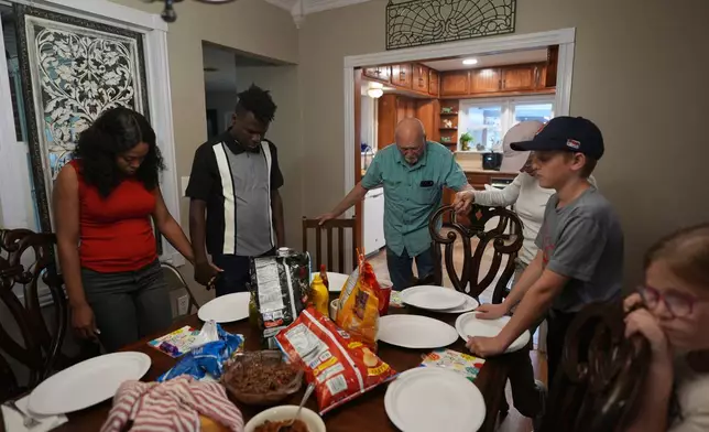 Haitian immigrants Sherlie Jean, left, holds hands with her husband Kevenson Jean during a prayer before eating with friends, Monday, April 14, 2025, in Panhandle, Texas. (AP Photo/Eric Gay)