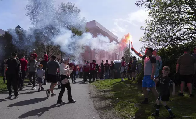 Supporters hold flares as red smoke fills the air outside of Anfield Road stadium ahead of the English Premier League soccer match between Liverpool and Tottenham Hotspur in Liverpool, England, Sunday, April 27, 2025. (AP Photo/Jon Super)