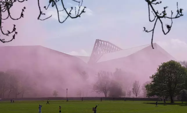 Red smoke fills the air outside of Anfield Road stadium ahead of the English Premier League soccer match between Liverpool and Tottenham Hotspur in Liverpool, England, Sunday, April 27, 2025. (AP Photo/Jon Super)
