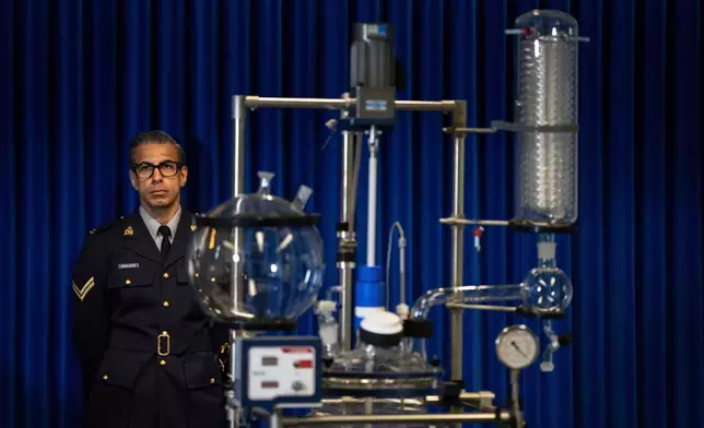 Constable Arash R Seyed stands with a double wall reaction vessel during a Royal Canadian Mounted Police (RCMP) news conference announcing fentanyl production labs that have been dismantled around British Columbia, in Surrey, British Columbia, Thursday, April 10, 2025. (Ethan Cairns/The Canadian Press via AP)
