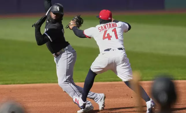 Chicago White Sox's Luis Robert Jr., left, is tagged out by Cleveland Guardians first baseman Carlos Santana (41) between first and second base on an attempted steal in the first inning of a baseball game in Cleveland, Tuesday, April 8, 2025. (AP Photo/Sue Ogrocki)
