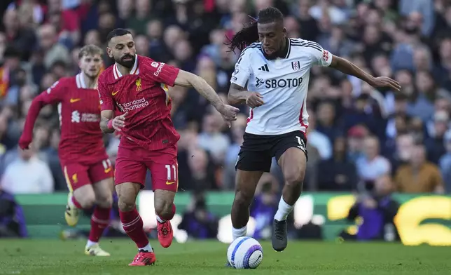 Fulham's Alex Iwobi, right, challenges for the ball with Liverpool's Mohamed Salah during the English Premier League soccer match between Fulham and Liverpool, at Craven Cottage, London, Sunday, April 6, 2025. (AP Photo/Kin Cheung)