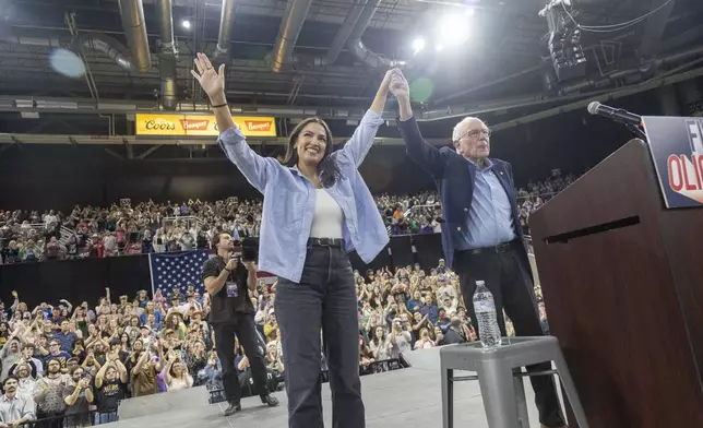 Rep. Alexandra Ocasio-Cortez, D-N.Y., holds hands with Sen. Bernie Sanders, I-Vt., during a "Fighting Oligarchy" event at the Ford Idaho Center in Nampa, Idaho, Monday, April 14, 2025. (AP Photo/Kyle Green)