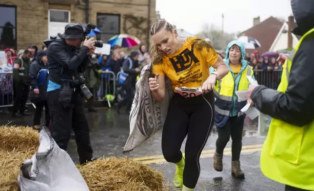 Jodie Ounsley, who plays Fury in the British TV show "Gladiators," reacts after finishing the women's open category race at the World Coal Carrying Championships in Ossett, West Yorkshire, England, Monday, April 21, 2025. (AP Photo/Jon Super)