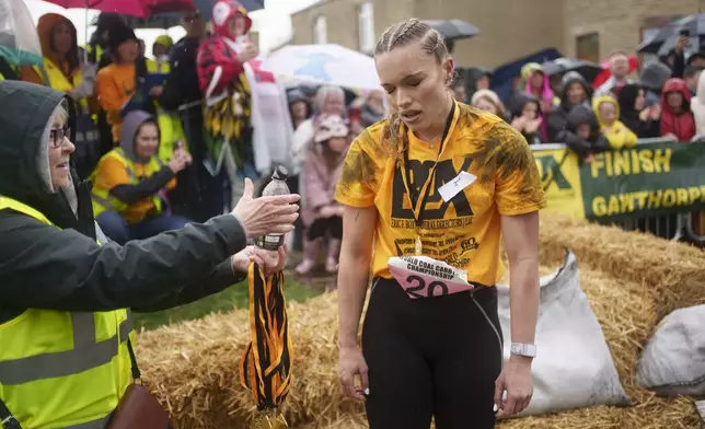 Jodie Ounsley, who plays Fury in the British TV show "Gladiators," reacts after finishing the women's open category race at the World Coal Carrying Championships in Ossett, West Yorkshire, England, Monday, April 21, 2025. (AP Photo/Jon Super)