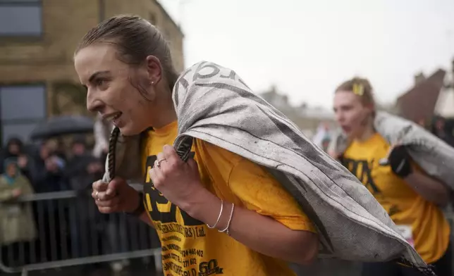 Women's race contestants make their way to the finish line, each carrying a 20kg sack of coal, at the World Coal Carrying Championships in Ossett, West Yorkshire, England, on Monday, April 21, 2025. (AP Photo/Jon Super)