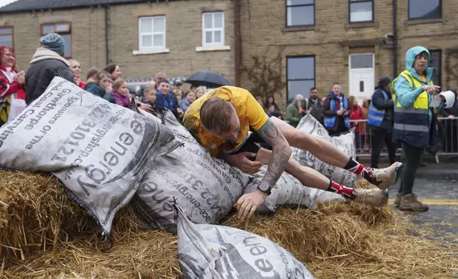 A contestant drops his bag after racing a 1.1 km course with a 50kg sack of coal during the World Coal Carrying Championships in Ossett, West Yorkshire, England, Monday, April 21, 2025. (AP Photo/Jon Super)