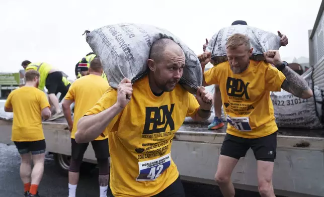 A contestant loads a 50kg bag of coal onto his shoulders during the men's open category at the World Coal Carrying Championships in Ossett, West Yorkshire, England, Monday, April 21, 2025. (AP Photo/Jon Super)