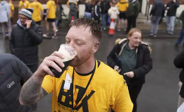 Contestant Brett Guilfoyle drinks a beer after competing in the World Coal Carrying Championships, where contestants carry a 50 kg bag of coal for just over a kilometre, in Ossett, West Yorkshire, England, Monday, April 21, 2025. (AP Photo/Jon Super)