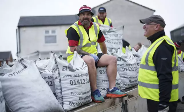 Volunteers from Ossett Rugby Club prepare to load contestants with sacks of coal during the World Coal Carrying Championships in Ossett, West Yorkshire, England, Monday, April 21, 2025. (AP Photo/Jon Super)
