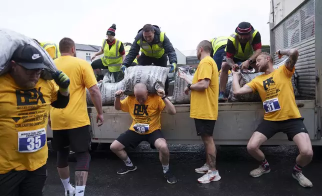 A contestant loads a 50kg bag of coal onto his shoulders during the World Coal Carrying Championships in Ossett, West Yorkshire, England, Monday, April 21, 2025. (AP Photo/Jon Super)